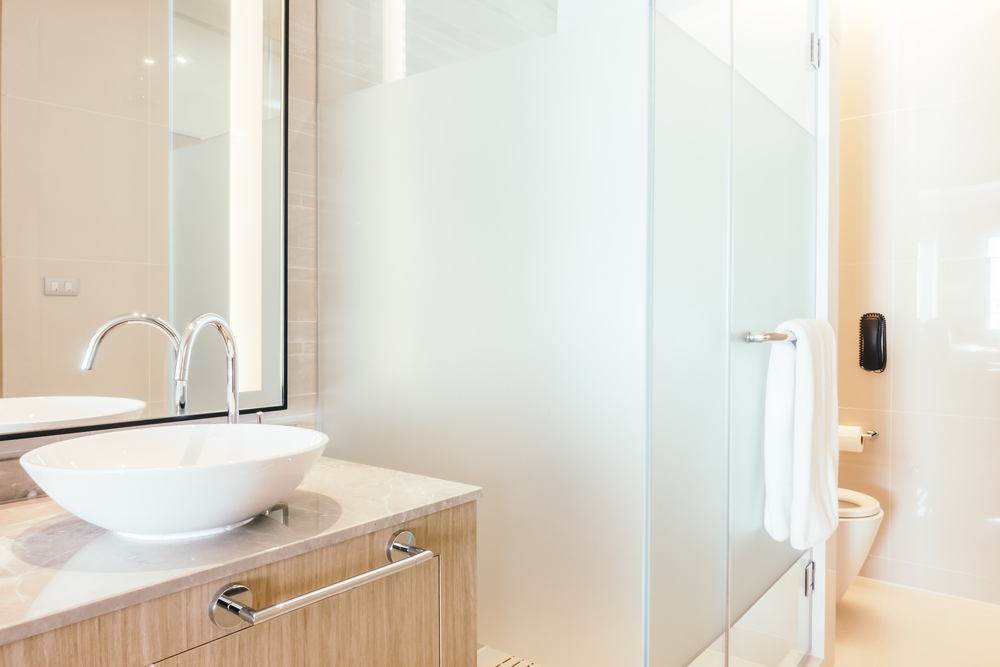 Baño elegante y funcional con accesorios modernos, incluyendo lavamanos de diseño, mampara de vidrio y toallero bien ubicado para mayor comodidad.